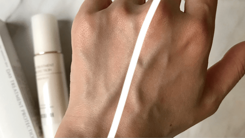 アクセーヌ デイトリートメントプロテクションを手の甲の半分に塗って白浮きしていないところを見せています。