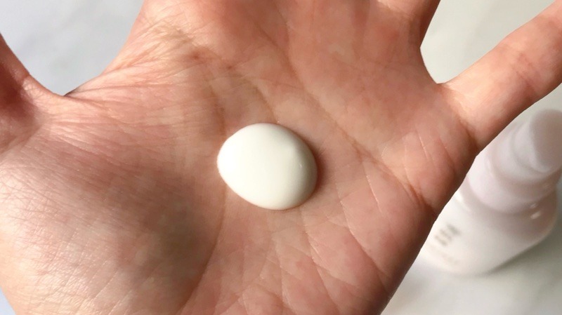 雪肌精クリアウェルネス モイストリペアミルクを手に出しています。